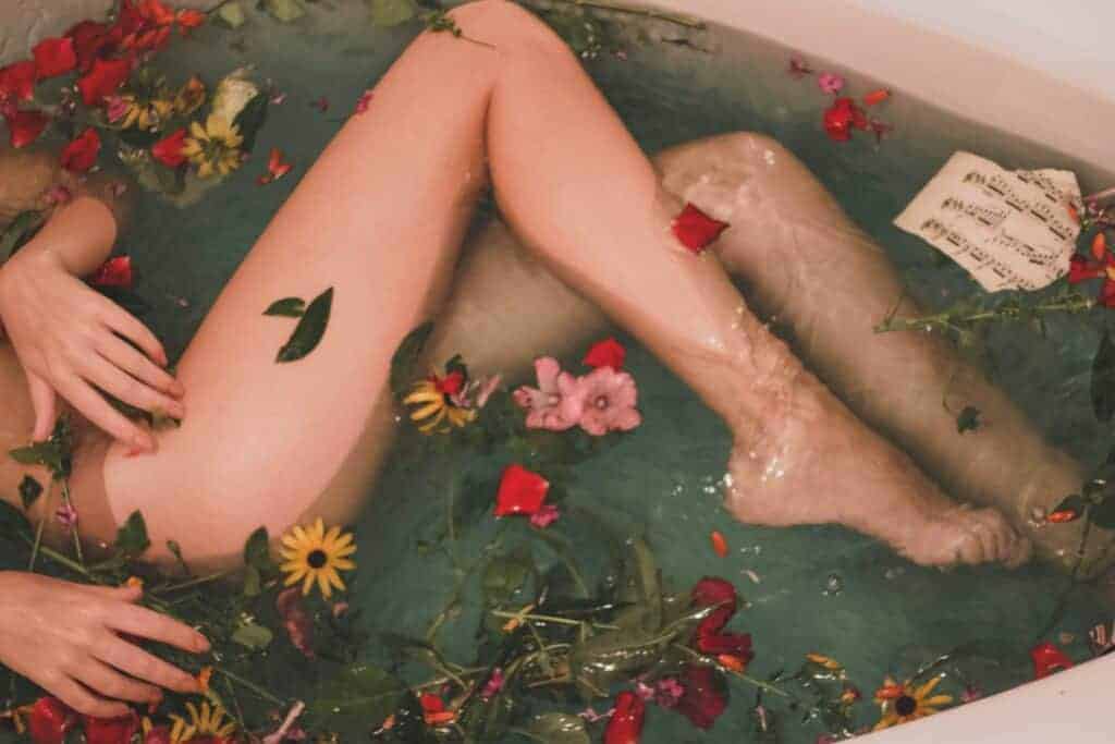 Gambe di donna in una vasca da bagno con rose nell'acqua