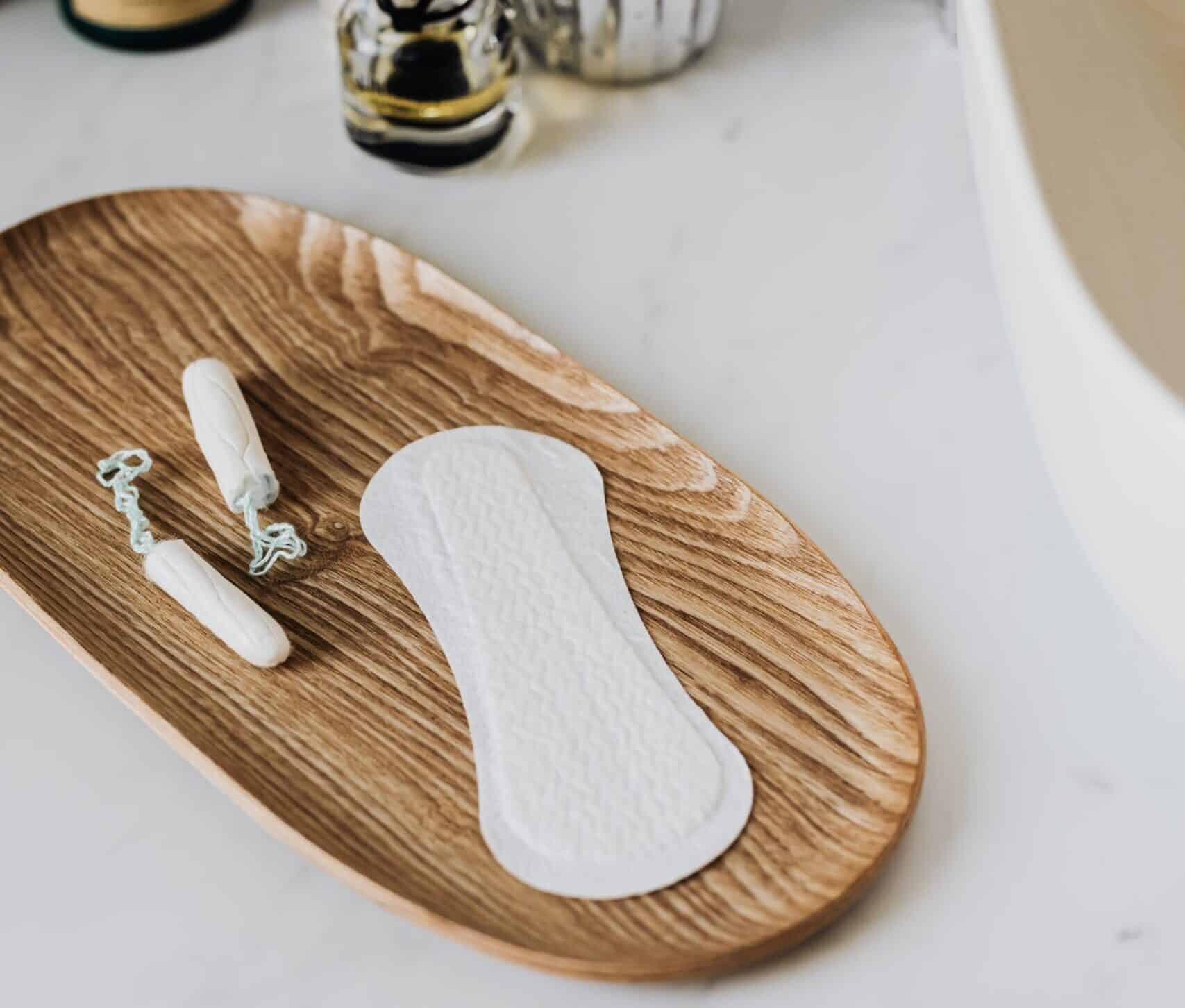 Sanitary napkin with tampons on a wooden tray in the bathroom